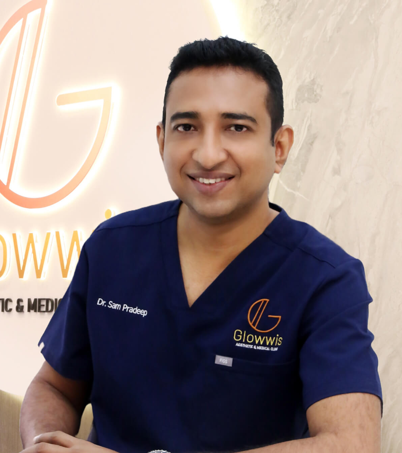 A smiling doctor wearing a blue medical uniform in front of a Glowwis Aesthetic & Medical Clinic sign.