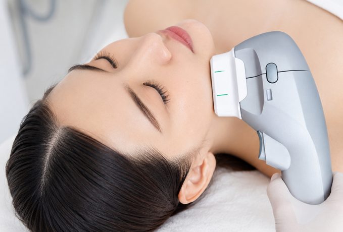 A close-up of a woman receiving HIFU treatment on her face in a medical setting.